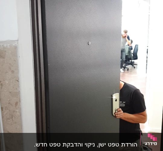אדם מתקין דלת מתכת עם ידית כסופה